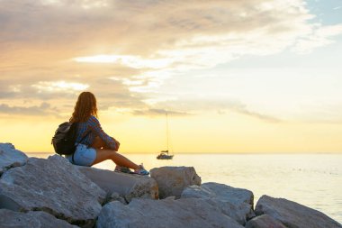 Sırt çantalı kadın gün batımını seyrediyor. Boşluğu kopyala