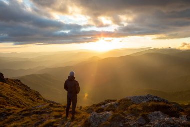 Dağların tepesinde gün batımını seyreden adamın silueti. yürüyüş kavramı