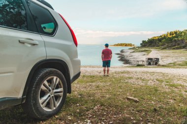 Öndeki sahil aracının önünde duran turist.