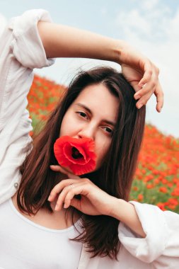 Haşhaş çiçekleri ile poz veren genç ve çekici bir kadın. Kapat.