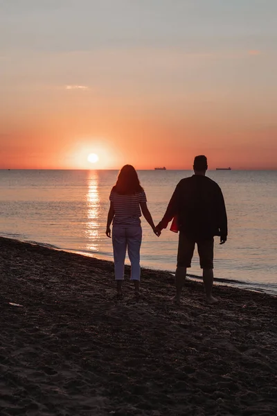 Пара Тримає Руки Дивлячись Захід Сонця Над Піщаним Морем — стокове фото