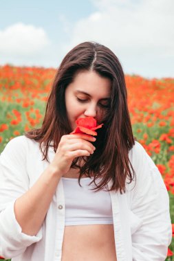 Haşhaş çiçekleri ile poz veren genç ve çekici bir kadın. Kapat.