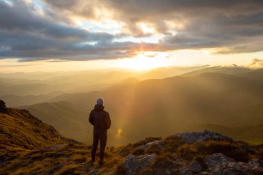 Dağların tepesinde gün batımını seyreden adamın silueti. yürüyüş kavramı