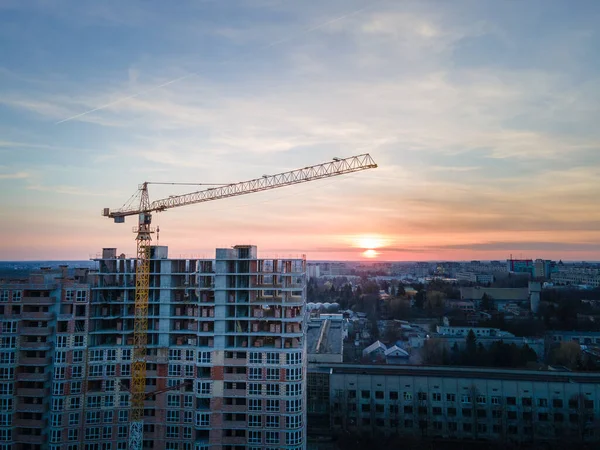 aerial view of apartment construction site with crane city development. sunset above city