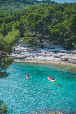 Pula, Hırvatistan - 31 Mayıs 2019: İnsanlar şeffaf deniz suyunda kayak yapıyor. yaz tatili