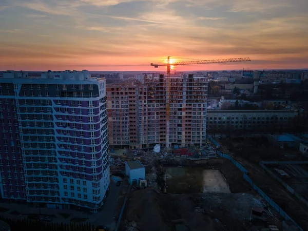 有起重机城市发展的公寓建筑工地的航拍图 日落在城市上空 — 图库照片