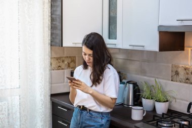 Sabah kahvesi içen bir kadın. Mutfakta internette sörf yapıyor. E-postaları kontrol ediyor.