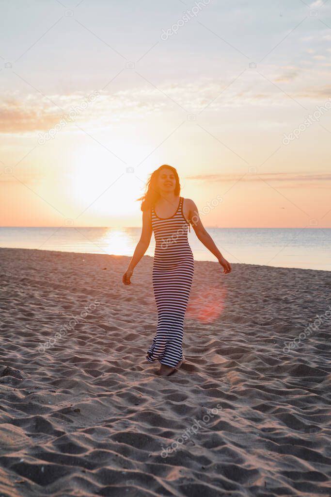 young beautiful sexy woman in dress walking bay sandy beach at sunset. summer vacation