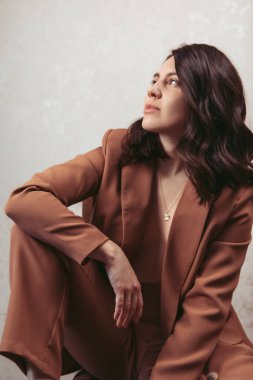 Kahverengi ceketli, stüdyo ışığı olan çekici genç bir kadının şehvetli portresi.