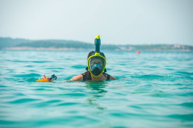 Şnorkelli kadın deniz suyunda maske takıyor.