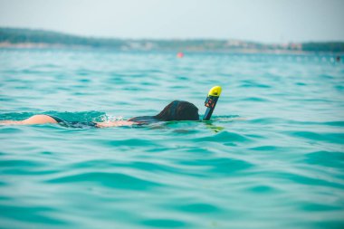 Şnorkelli kadın deniz suyunda maske takıyor.