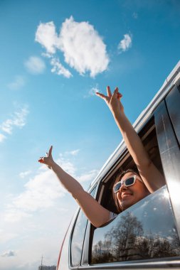 Kadın gülen suratla arabadan dışarı çıktı. Güneşli bir gün. mavi gökyüzü