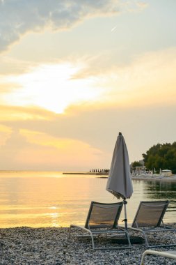 Güneş pansiyonları ve şemsiyeli deniz sahili manzarası. Boşluğu kopyala