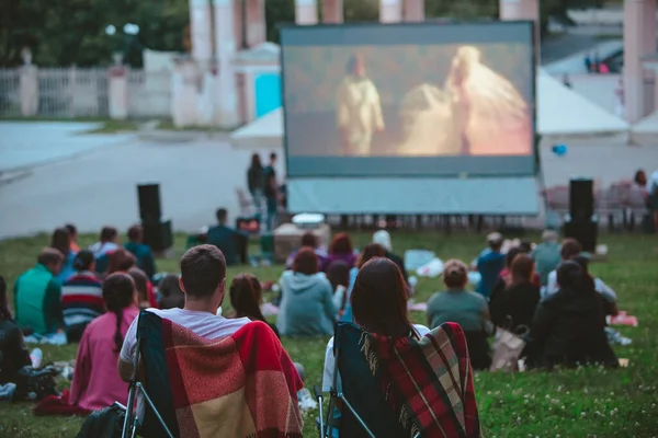 Halk parkındaki açık hava sinemasında kamp sandalyesinde oturan çift.