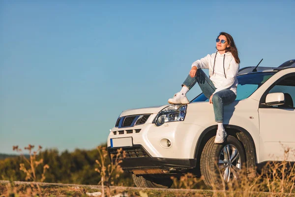 Mulher perto branco suv carro apreciando por do sol — Fotografia de Stock