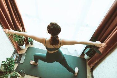 Kadın büyük pencerenin yanında yoga yapıyor. Sağlıklı bir yaşam tarzı.