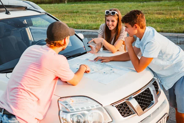 friends planning travel destination at car hood sunny day