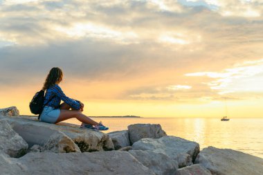 Sırt çantalı kadın gün batımını seyrediyor. Boşluğu kopyala
