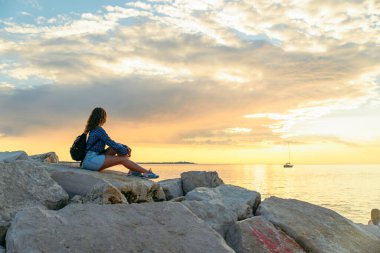 Sırt çantalı kadın gün batımını seyrediyor. Boşluğu kopyala