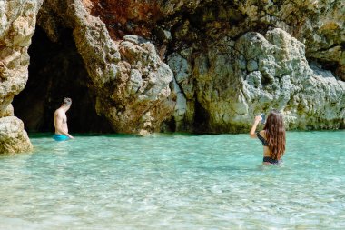 Pula, Hırvatistan - 1 Haziran 2019: mağara yakınlarında deniz suyunda mayo giyen güzel bir kadın. arka plan