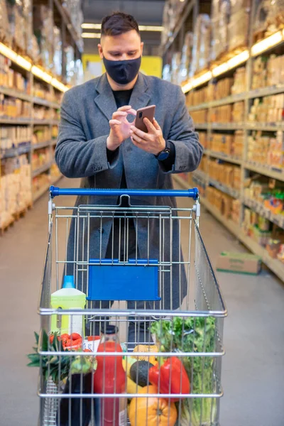 Man Grocery Store Cart Checking Phone Copy Space — Stock Photo, Image