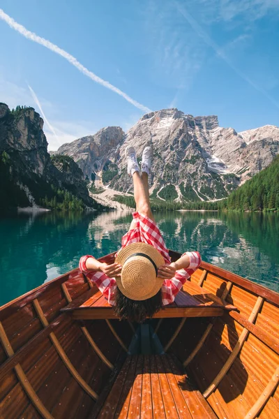 woman sitting in big brown boat at lago di braies lake in Italy. summer vacation