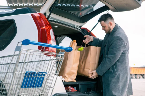 Mann Legt Tüten Mit Produkt Kofferraum — Stockfoto