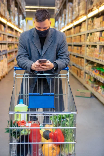 Mann Lebensmittelgeschäft Mit Einkaufswagen Kontrolliert Telefonkopierplatz — Stockfoto