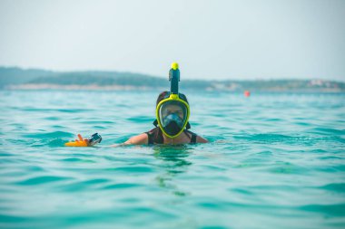 Şnorkelli kadın deniz suyunda maske takıyor.