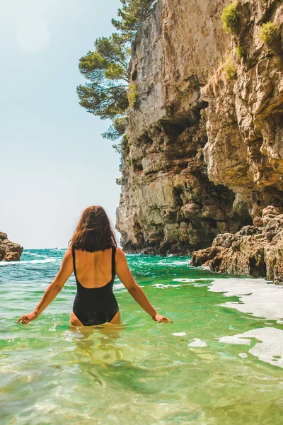 Wanita Dewasa Muda Berbaju Renang Hitam Berjalan Laut Diantara Tebing — Stok Foto