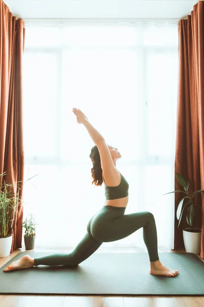 女人在家里大窗户旁边做瑜伽 过着健康的生活 — 图库照片
