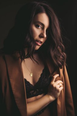 Kahverengi ceketli, stüdyo ışığı olan çekici genç bir kadının şehvetli portresi.