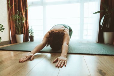 Kadın büyük pencerenin yanında yoga yapıyor. Sağlıklı bir yaşam tarzı.