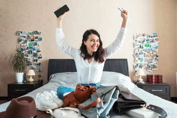 woman with phone and bank card sitting on the bed with lot of stuff online shopping