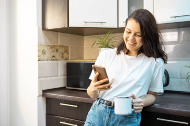 Sabah kahvesi içen bir kadın. Mutfakta internette sörf yapıyor. E-postaları kontrol ediyor.