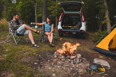Portatif koltuklarda oturan bir çift çay içip sohbet ediyorlar. kamp yaz aktiviteleri kopyalama alanı