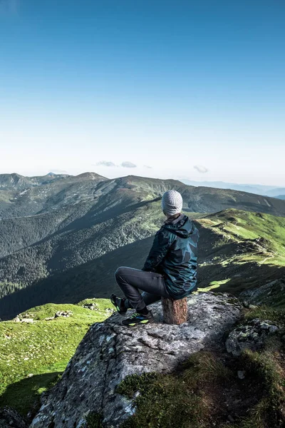 男は山の頂上に座って景色を楽しんでいる コピースペース — ストック写真