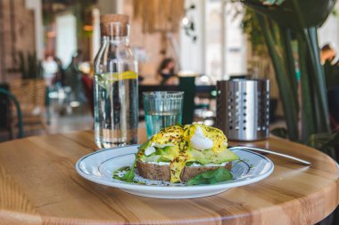 Lokantada avokado ve yumurtalı tost. Kahverengi renkler. Boşluğu kopyala.