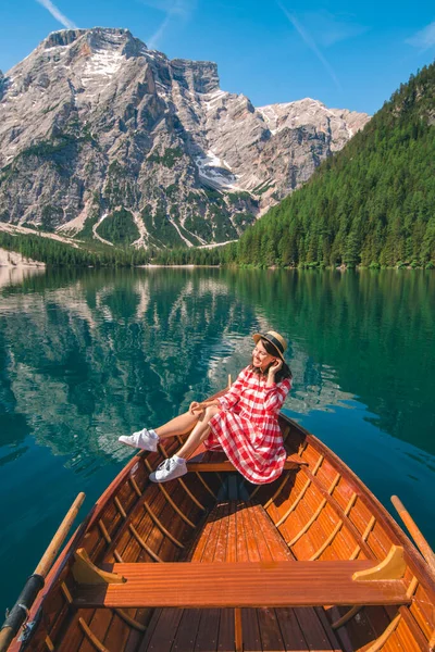 woman sitting in big brown boat at lago di braies lake in Italy. summer vacation