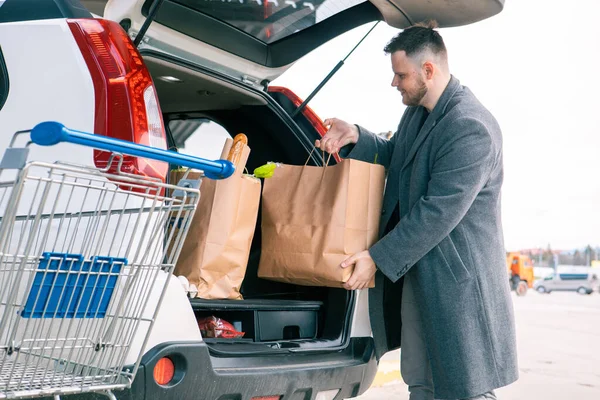 Mann Legt Tüten Mit Produkt Kofferraum — Stockfoto