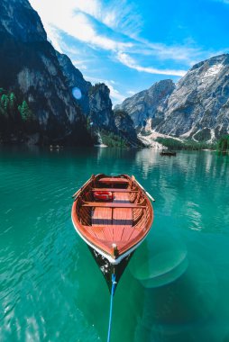 Dağ gölünün berrak mavi suyunda kahverengi ahşap bir tekne. Boşluğu kopyala