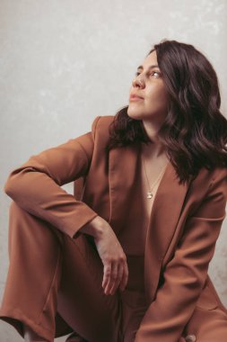 Kahverengi ceketli, stüdyo ışığı olan çekici genç bir kadının şehvetli portresi.