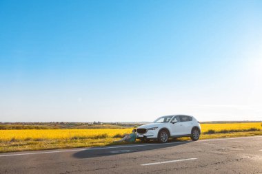 Adam gezgin gün batımında yarış pistinin kenarında arabanın yanında oturuyor. Kopyalama uzayı.