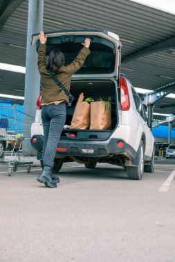 Kadın, market fotokopi alanından sonra çantalarını araba bagajına koydu.