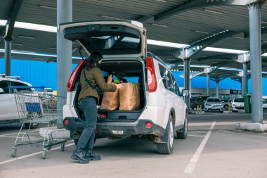 Gülümseyen kadın, market fotokopi alanından sonra bagaja ürünleri koyuyordu.