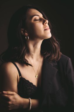 Kahverengi ceketli, stüdyo ışığı olan çekici genç bir kadının şehvetli portresi.