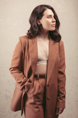 Kahverengi ceketli, stüdyo ışığı olan çekici genç bir kadının şehvetli portresi.