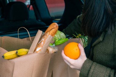 Gülümseyen kadın, market fotokopi alanından sonra bagaja ürünleri koyuyordu.