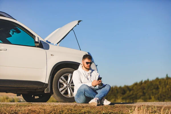 Mann Sitzt Bei Sonnenuntergang Neben Auto Mit Geöffneter Motorhaube Und — Stockfoto