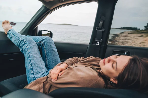 woman resting in car parked at sea beach. summer vacation